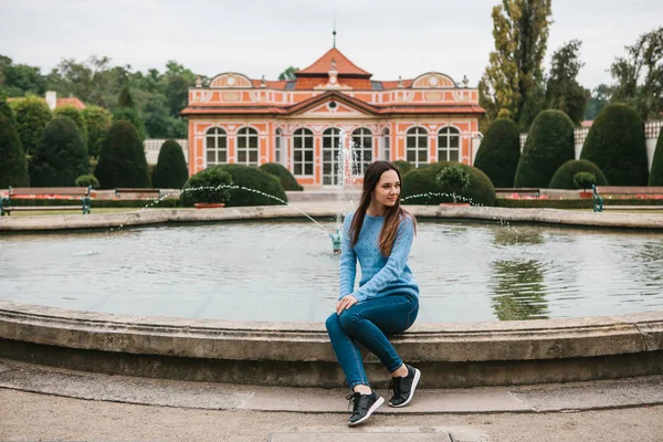 Güzel genç kız parkta bir çeşme yanında oturur ve bir dinlenme vardır