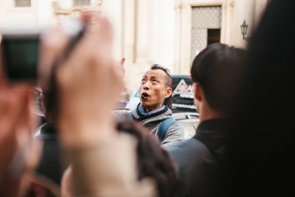 Prague, September 21, 2017: Asian guide emotionally tells Asian tourists about the sights of the city and interesting places. Prague is one of the favorite cities for tourists