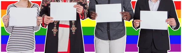 Люди разных национальностей держат пустые простыни на фоне флага ЛГБТ. Концепция свободы и прав человека — стоковое фото