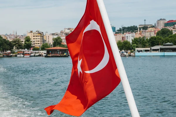 The national Turkish flag flutters in the wind against the backdrop of the Bosphorus and Istanbul blurred in the background — Stock Photo, Image