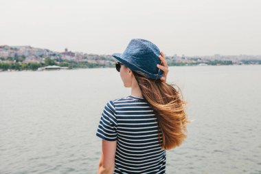 Şapkalı bir genç güzel kız bir tatil Türkiye ve Boğaz'ın ve Istanbul uzaktan güzel manzaralarını keyif alıyor