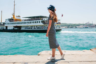 Şapkalı bir genç güzel kız bir tatil Türkiye ve Boğaz'ın ve Istanbul uzaktan güzel manzaralarını keyif alıyor. Bir gemi veya bir yolcu arka planda su üzerinde yüzen tekne
