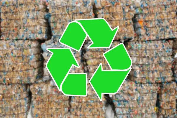 Sign recycling waste. The pile of waste is blurred in the background