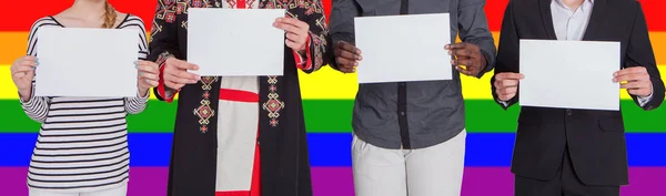 Pessoas de diferentes nacionalidades estão segurando folhas vazias contra o pano de fundo da bandeira LGBT. O conceito de liberdade e direitos humanos — Fotografia de Stock