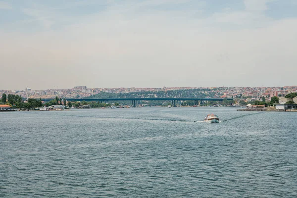スピード ボートは、イスタンブールのボスポラス海峡に沿って帆します。バック グラウンドで都市建築 — ストック写真