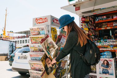 Istanbul, 17 Haziran 2017: Şapkalı bir sırt çantası ile genç güzel kız satın bir dergi veya gazete bir sokak basın mağaza