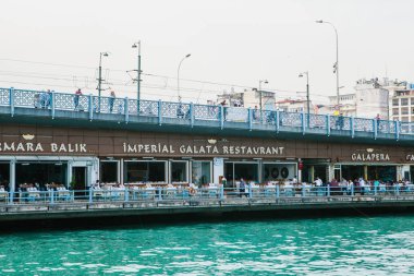 Istanbul, 17 Haziran 2017: Galata Köprüsü üzerinde yürüyen insanlar. Köprünün altından müşterilerle Cafe
