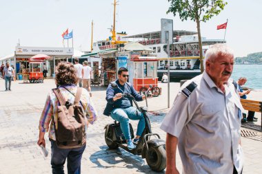 Istanbul, 17 Haziran 2017: Bir adam ya da bir delikanlı şehri bir elektrikli scooter ya da bisikletle sokak kullanıyor. Yakınlarda yerliler kendi iş bulunmaktadır. Sıradan şehir hayatı ya da günlük yaşam