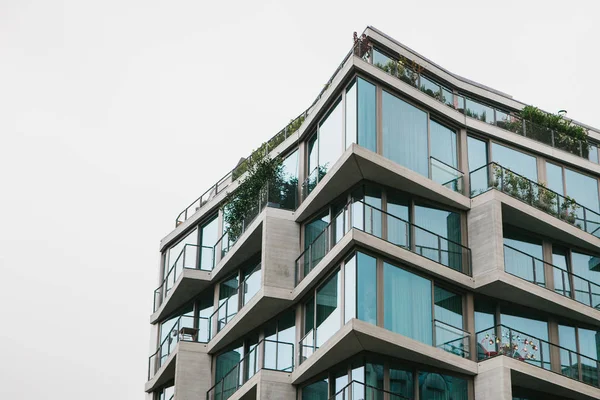 Hörnet av byggnaden med många fönster mot den grå himlen — Stockfoto