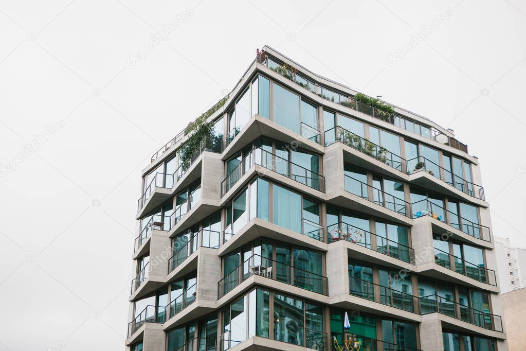 The corner of the building with many windows against the gray sky