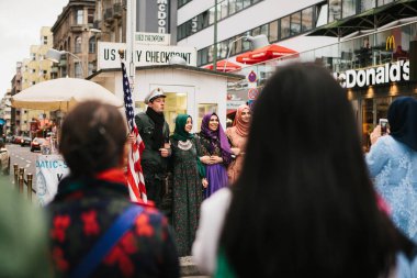 Berlin, 1 Ekim 2017: turist Chekpoint Charlie denilen bir ünlü şehir cazibe yanındaki fotoğrafı olumlu Arap kadın. Yakınlarda başka turist bulunmaktadır ve onlara bakmak