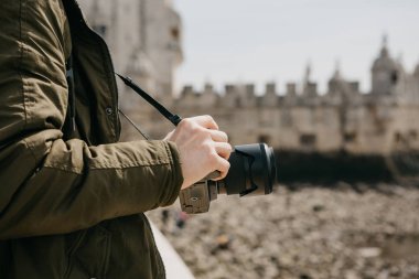 Profesyonel bir fotoğrafçı ya da bir genç erkek turist fotoğrafları Lizbon Portekiz manzaraları. Bir kamera tutar. Torre de Belem görünürde arka plan bulanık.