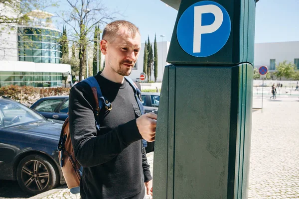 A man pays for parking using a special machine to pay in Lisbon in Portugal