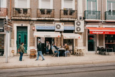 Lisbon, 18 Haziran 2018: Bir grup adam veya arkadaş restoranın yanındaki sokakta oturan, şarap içme ve konuşmak. Yerel sakinlerinin her zamanki kentsel yaşam