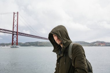 Genç bir seyahat veya bir turist Lizbon Portekiz Waterfront 25 Nisan köprünün yanındaki bir sırt çantası ile