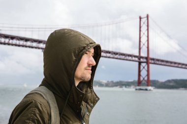 Genç bir seyahat veya bir turist Lizbon Portekiz Waterfront 25 Nisan köprünün yanındaki bir sırt çantası ile