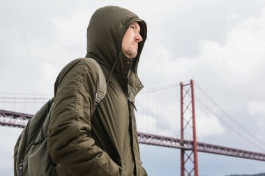 Genç bir seyahat veya bir turist Lizbon Portekiz Waterfront 25 Nisan köprünün yanındaki bir sırt çantası ile