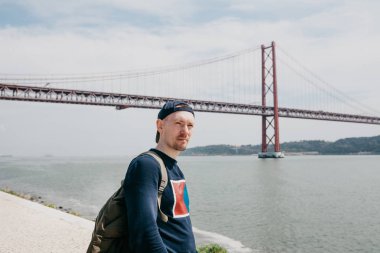 Genç bir seyahat veya bir turist Lizbon Portekiz Waterfront 25 Nisan köprünün yanındaki bir sırt çantası ile