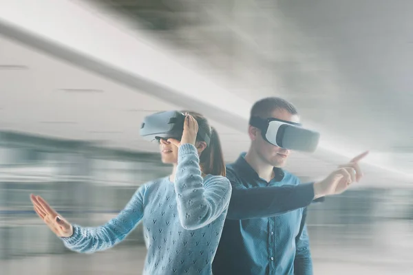 Uma jovem mulher e um jovem em vidros de realidade virtual.O conceito de tecnologias e tecnologias modernas do futuro. óculos VR . — Fotografia de Stock
