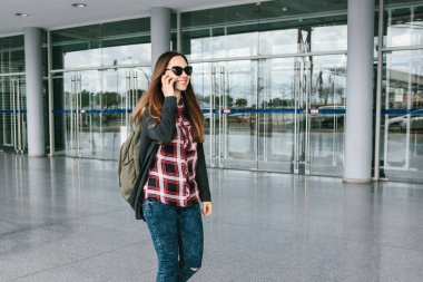 Genç güzel turist kız havaalanında veya alışveriş merkezi veya İstasyonu yakınında bir taksi ya da bir cep telefonu üzerinde konuşurken ya da bir cep telefonu kullanarak arkadaşlarıma söz çağırır