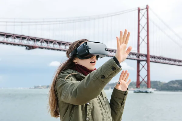 Красивою дівчиною в окулярах віртуальної реальності. 25 квітня мосту в Лісабоні у фоновому режимі. Концепція сучасні технології та їх застосування у повсякденному житті — стокове фото