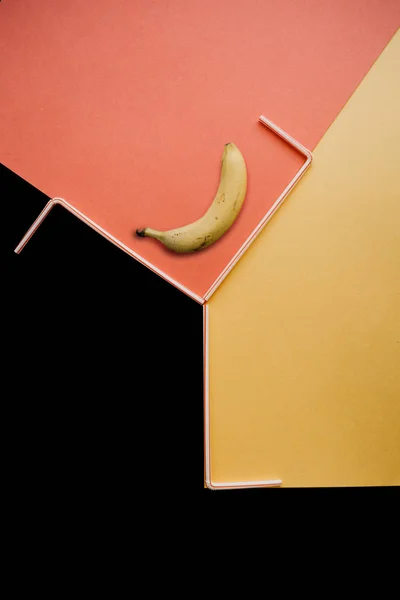 Una fotografía creativa con un plátano y tubos pequeños sobre un fondo brillante — Foto de Stock