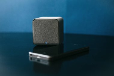 Bir kablosuz hoparlör ve karanlık bir arka plan bir cep telefonundan yanında. Bir cep telefonu müzik dinlemek için Modern teknoloji