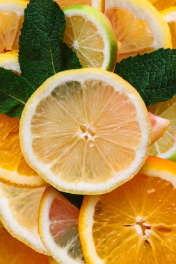 Narenciye arka plan. Birçok dilim limon, portakal, limon ve nane yaprakları yalan birlikte. Bir sürü meyve. Sağlıklı yemek ve vitaminler