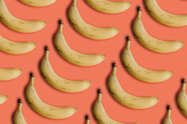 ピンクの背景の行の多くのバナナ — ストック写真