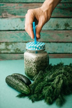 Vejetaryen yeşil sebze ve meyve kokteyli salatalık ve yeşil maydanoz ve dereotu karışımı. Kişi bir el ile bir kavanoz içecek alır.