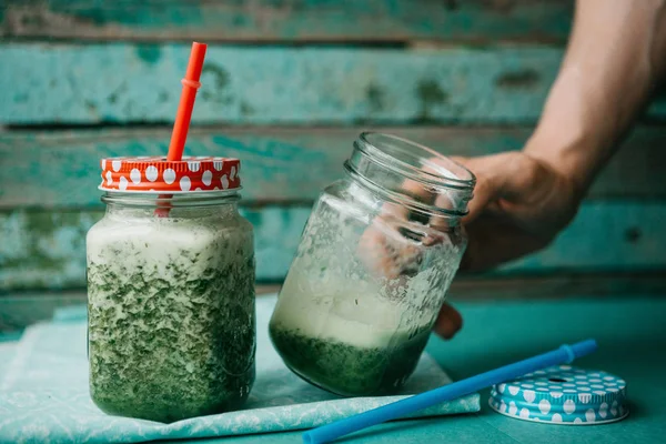 Vejetaryen yeşil sebze ve meyve kokteyli salatalık ve yeşil maydanoz ve dereotu karışımı. Kişi bir el ile bir kavanoz içecek alır.