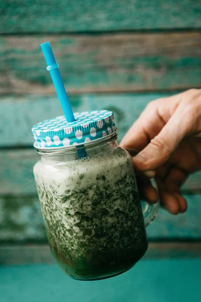 Vejetaryen yeşil sebze ve meyve kokteyli salatalık ve yeşil maydanoz ve dereotu karışımı. Kişi bir el ile bir kavanoz içecek alır.