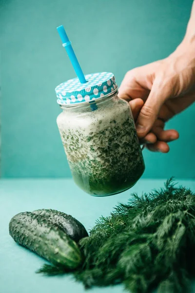 Vejetaryen yeşil sebze ve meyve kokteyli salatalık ve yeşil maydanoz ve dereotu karışımı. Kişi bir el ile bir kavanoz içecek alır.