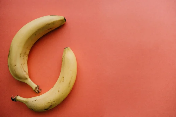 ピンクの背景の 2 つの熟したバナナ。栄養価の高い、健康食品 — ストック写真