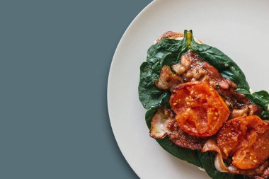 Yakın çekim. Lezzetli ve besleyici tost ya da sandviç sosis, ıspanak ve domates üzerinde gri bir arka plan ile. Lezzetli yemekler. Metin için yakındaki yer