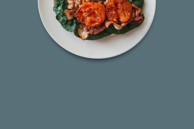 Pastırma, ıspanak ve gri arka plan üzerinde domates ile lezzetli ve besleyici yemek. Lezzetli yemekler. Aşağıda metin için bir yer