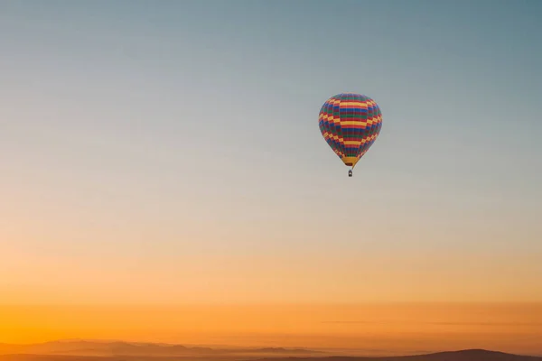 Voo de um balão solitário no céu pela manhã ao nascer do sol ou à noite ao pôr do sol. Viajar por via aérea ou aventura — Fotografia de Stock