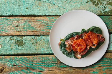 Lezzetli ve besleyici tost ya da sandviç sosis, ıspanak ve bir ahşap yüzey üzerinde domates ile. Lezzetli yemekler. Metin için yakındaki yer