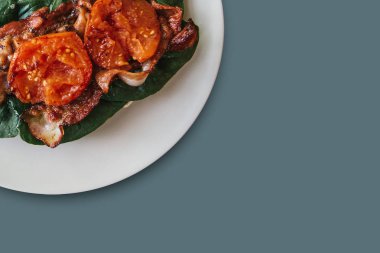 Yakın çekim. Pastırma, ıspanak ve gri arka plan üzerinde domates ile lezzetli ve besleyici yemek. Lezzetli yemekler. Metin için yakındaki yer