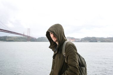 Genç bir seyahat veya bir turist Lizbon Portekiz Waterfront 25 Nisan köprünün yanındaki bir sırt çantası ile