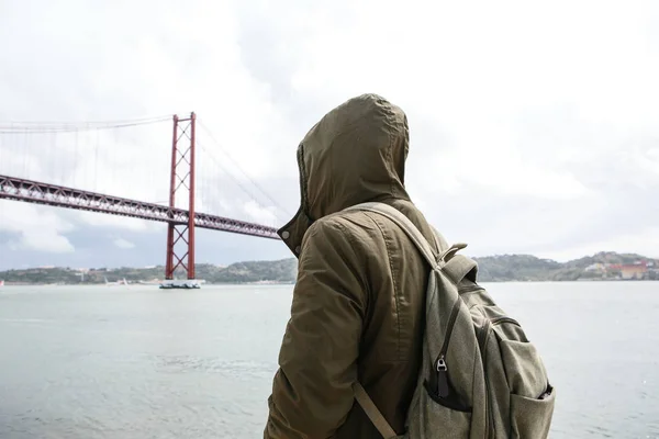 Mladý cestovatel nebo turista s batohem na nábřeží v Lisabonu v Portugalsku vedle 25. dubna most — Stock fotografie