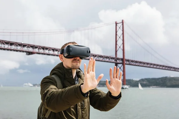 Людина використовує віртуальну реальність окуляри. 25 квітня мосту в Лісабоні у фоновому режимі. Концепція віртуальних подорожі. Концепція сучасні технології та їх застосування у повсякденному житті — стокове фото