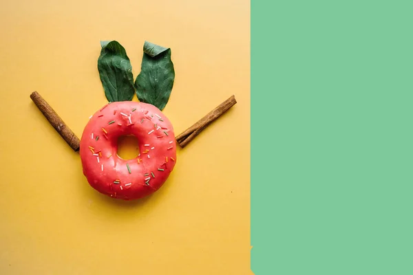 Un donut creativo con orejas de hojas que se asemejan a un conejo sobre un fondo de color en un estilo minimalista. Lugar cercano para el texto — Foto de Stock