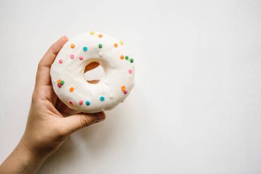 Bir el çörek beyaz bir arka plan üzerinde tutar. Yaratıcı fikir