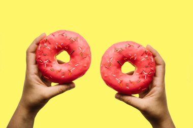 Kız iki kırmızı donut sarı bir arka plan üzerinde onun elinde tutuyor