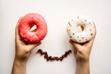 Kız çörek beyaz zemin üzerine onun elinde tutuyor. Çörek gülümsüyor gözleri ile pozitif bir insan gibi görünüyor