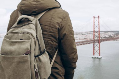 Genç bir seyahat veya bir turist Lizbon Portekiz Waterfront 25 Nisan köprünün yanındaki bir sırt çantası ile.