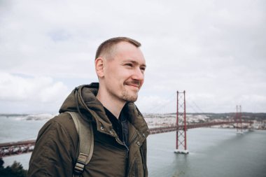 Genç bir seyahat veya bir turist Lizbon Portekiz Waterfront 25 Nisan köprünün yanındaki bir sırt çantası ile