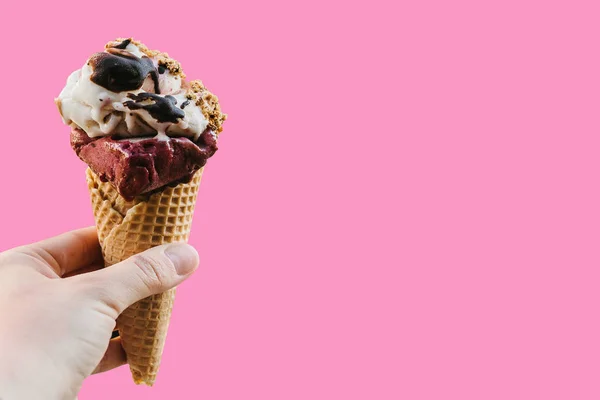 The girl is holding a delicious ice cream in her hand in a minimal style on a pink background. Summer concept