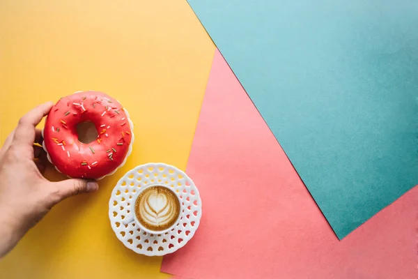 The girl is going to drink coffee and eat donut which lie on the colored surface — Stock Photo, Image